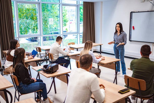 Students sitting in a classroom listening to their  teacher