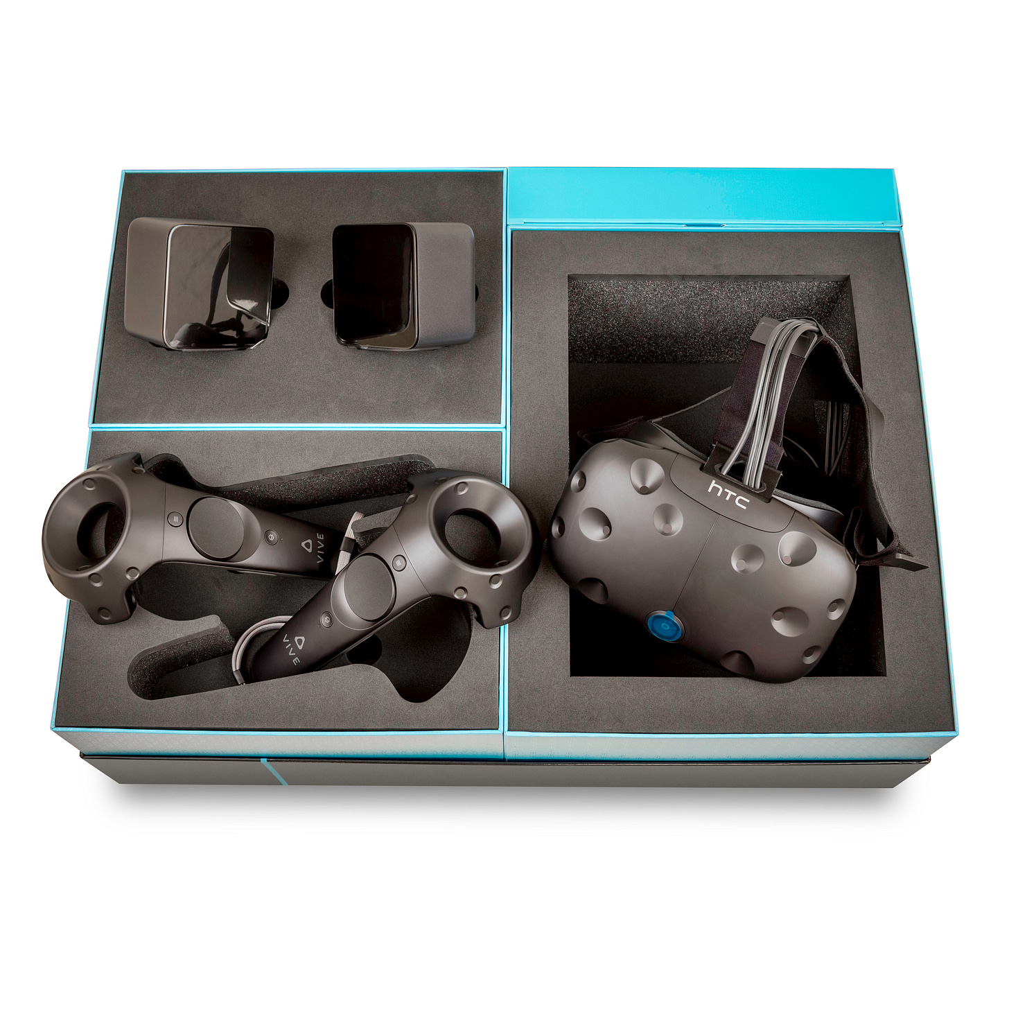 Top-down photo of an open product box containing a bulky HTC Vive headset, two hand controllers, and two boxy sensors. Top-down photo of an open product box containing a bulky HTC Vive headset, two hand controllers, and two boxy sensors.