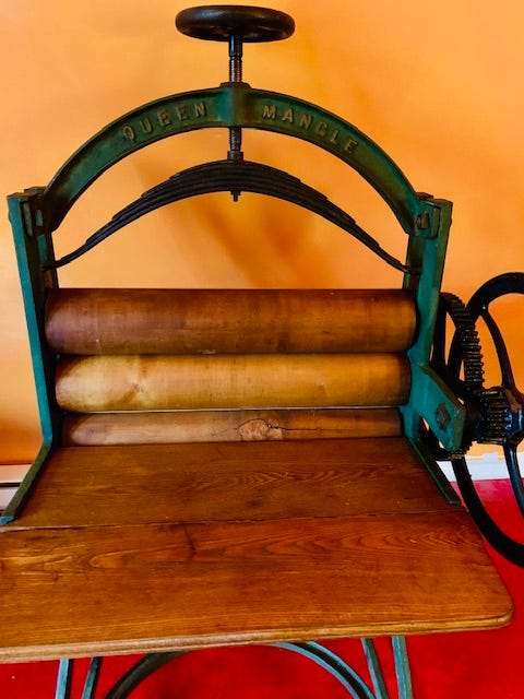 A large antique laundry mangle with cranks and gears and wooden rollers