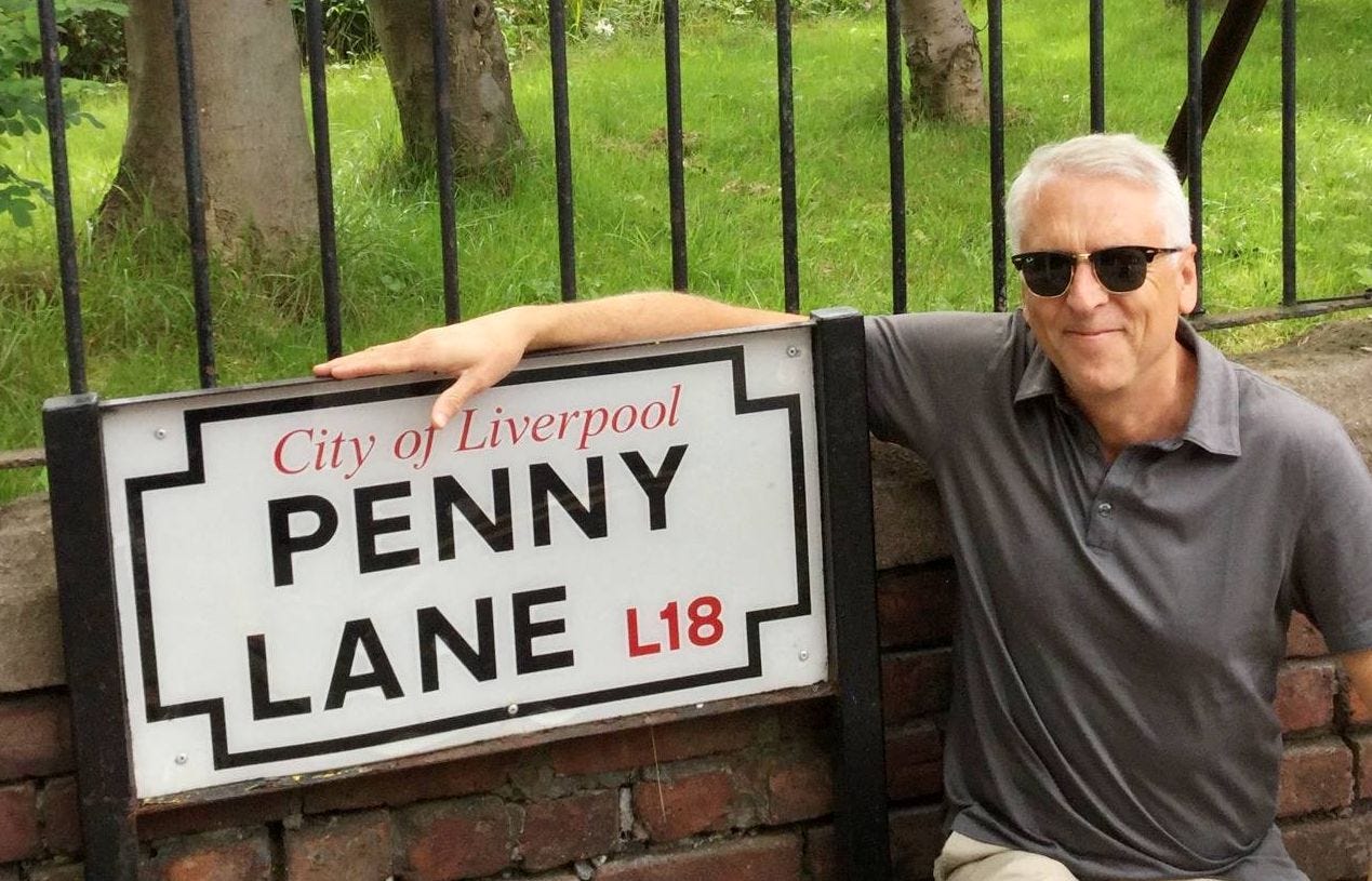 Alex Markham next to the Penny Lane street sign in Liverpool