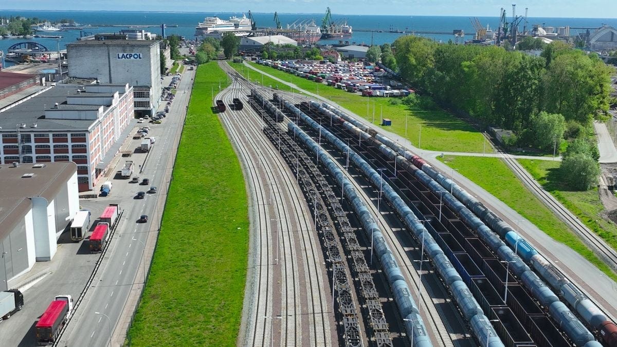 freight trains with cargo wagons on multiple railway tracks near Gdańsk port, Poland, with port cranes and container terminal in background freight trains with cargo wagons on multiple railway tracks near Gdańsk port, Poland, with port cranes and container terminal in background