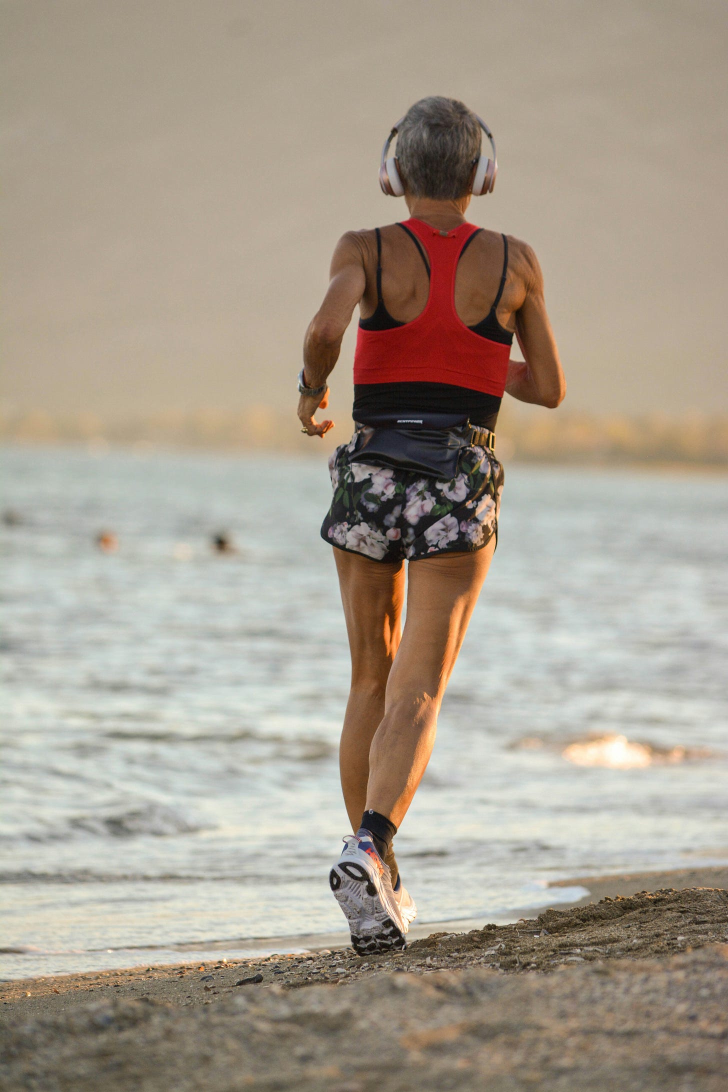 Woman running along the beach. Woman in menopause running. 