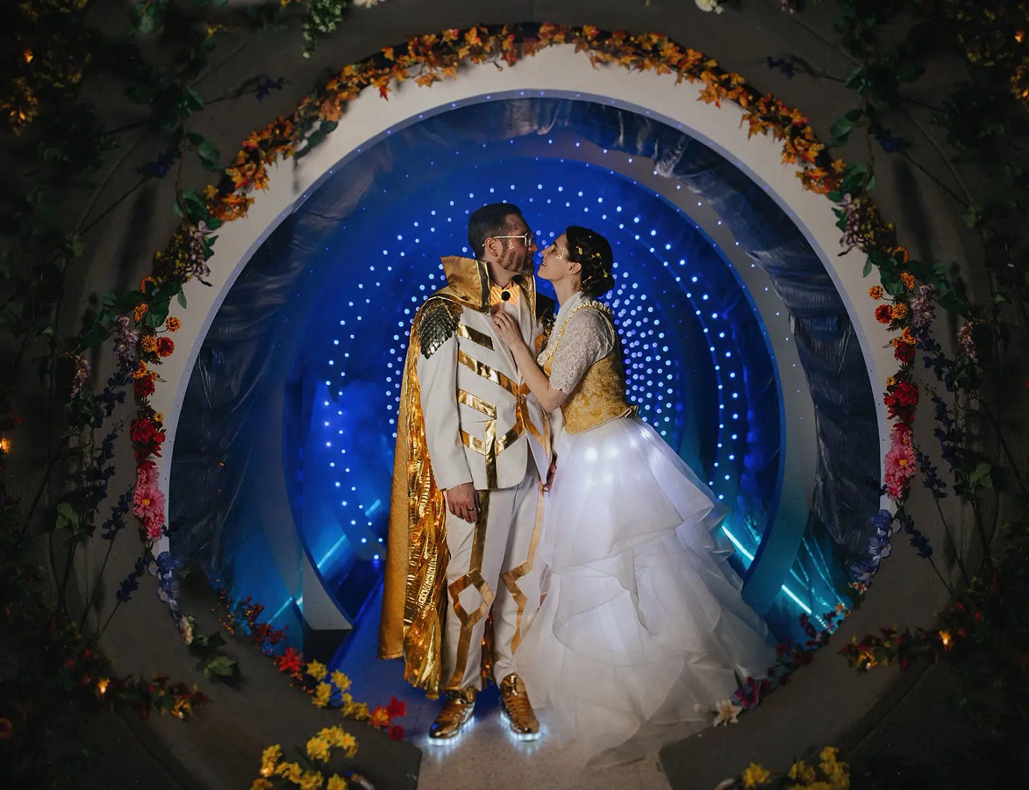 Amanda Knox and husband Chris Robinson embrace in front of a sci-fi tunnel of flowers and lights at their time traveler-themed wedding