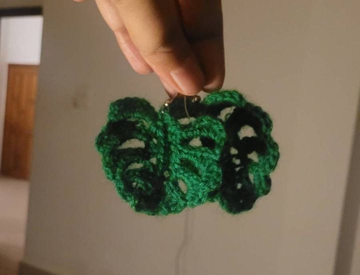 Crocheted green earrings shaped like monsterra leaves.