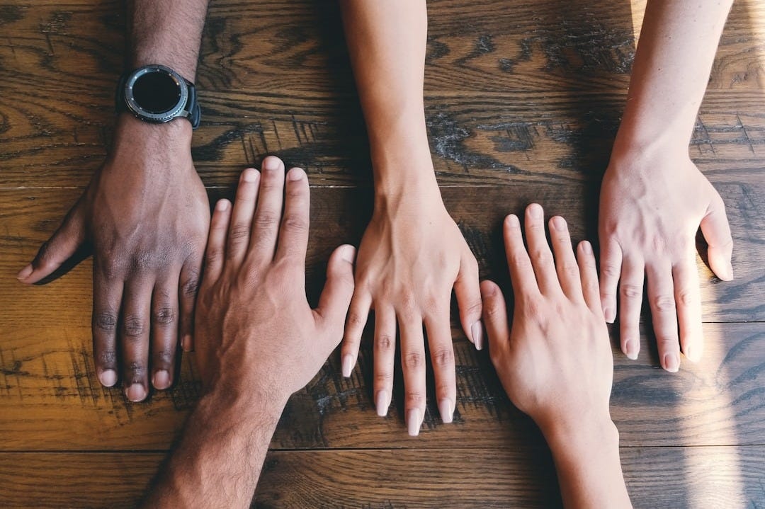 five human hands on brown surface five human hands on brown surface