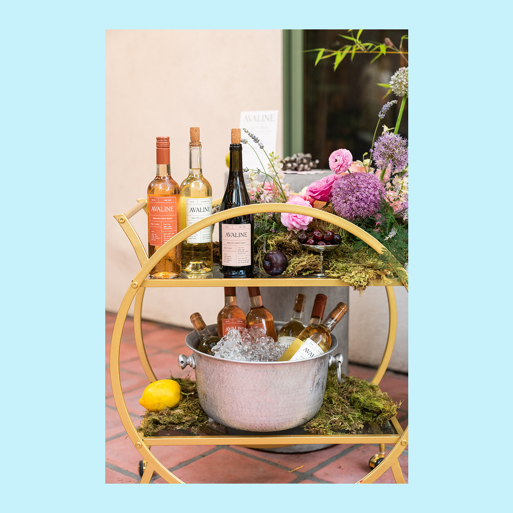 A simple yet cute bar cart with wine bottles on it.