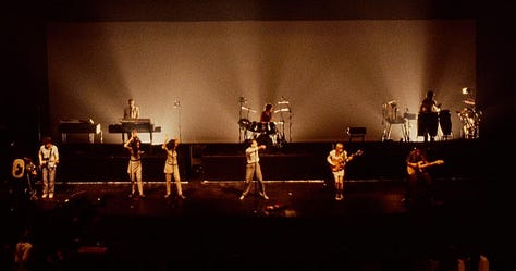 selects from Talking Heads' concert film Stop Making Sense. images of Byrne holding a microphone to camera, raising his arms, dancing in a big suit an with a lamp and full shots of the band.