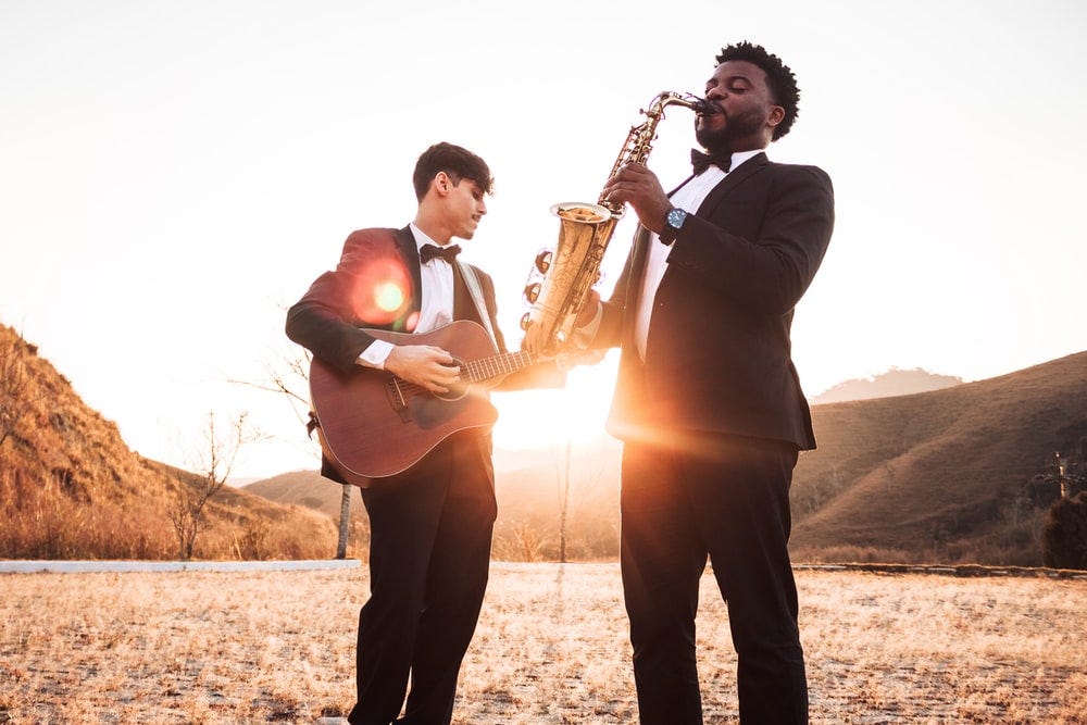 two men playing saxophone and guitar two men playing saxophone and guitar