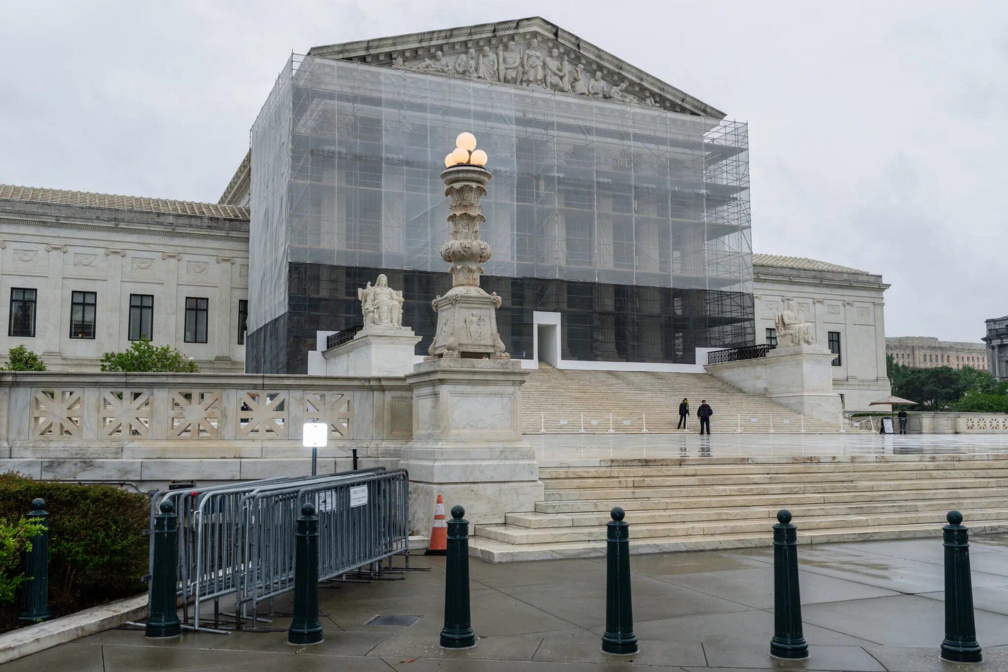 A photo of the outside of the US Supreme Court Building on a grey and rainy day. Scaffolding covers the outside of the building.