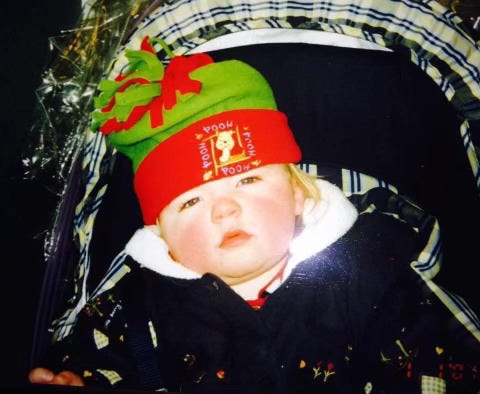 A film photograph of me as a baby sitting in a pram with a Winnie The Pooh hat