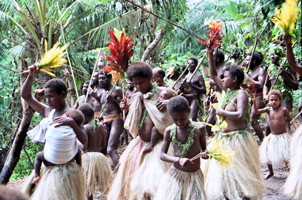 Vanuatan women dancing, palm trees behind