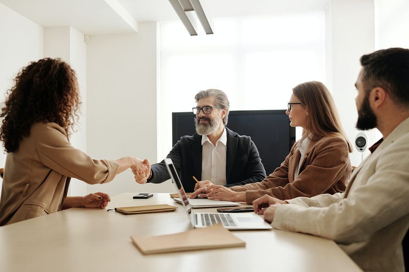 Four professionals ranged around a conference room desk.