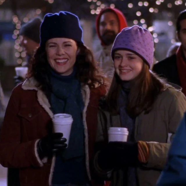 Lorelai and Rory drinking their coffees and bundled up in their little jackets and laughing very adorably