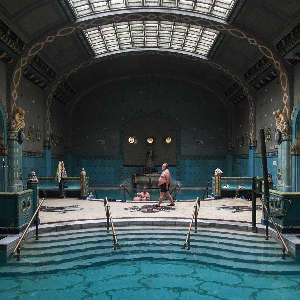 A blue indoor pool set inside a baroque hall.