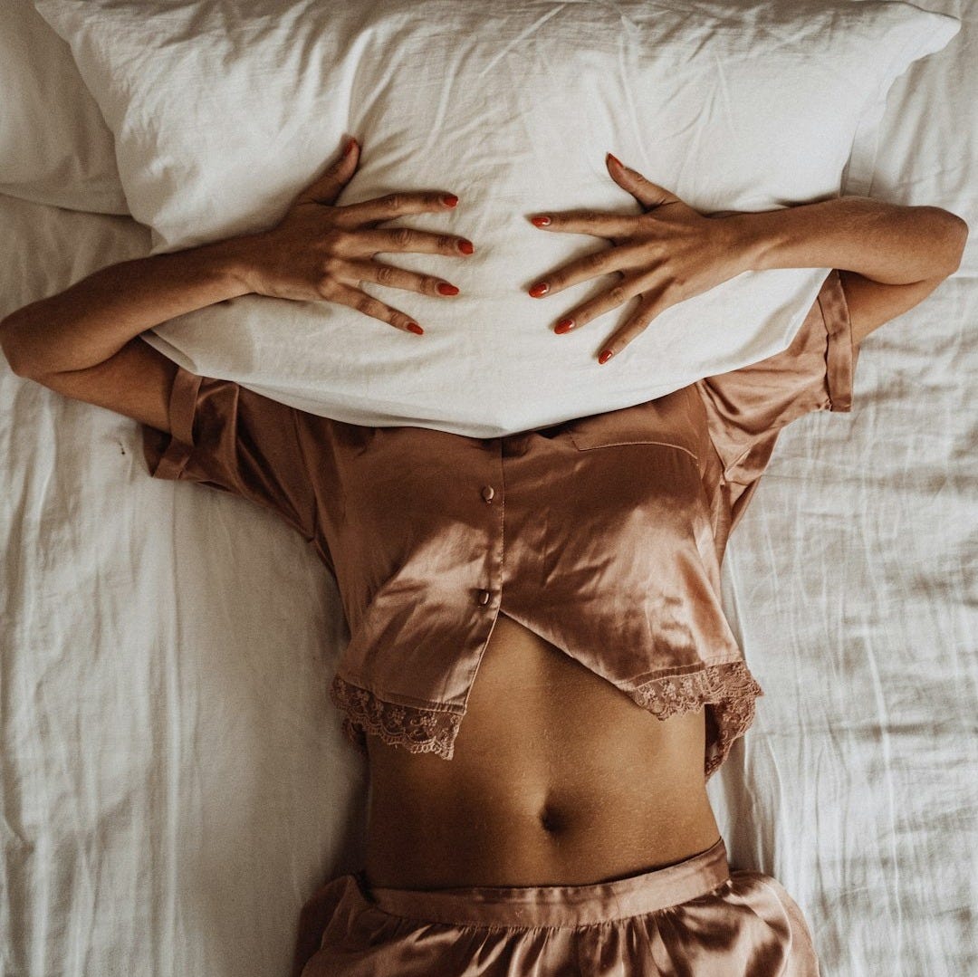 a woman laying in bed with her hands on a pillow a woman laying in bed with her hands on a pillow