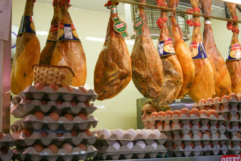Ham legs and fresh eggs at a local food market in Spain