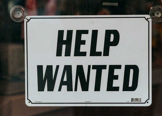 a sign that says help wanted on a glass door a sign that says help wanted on a glass door