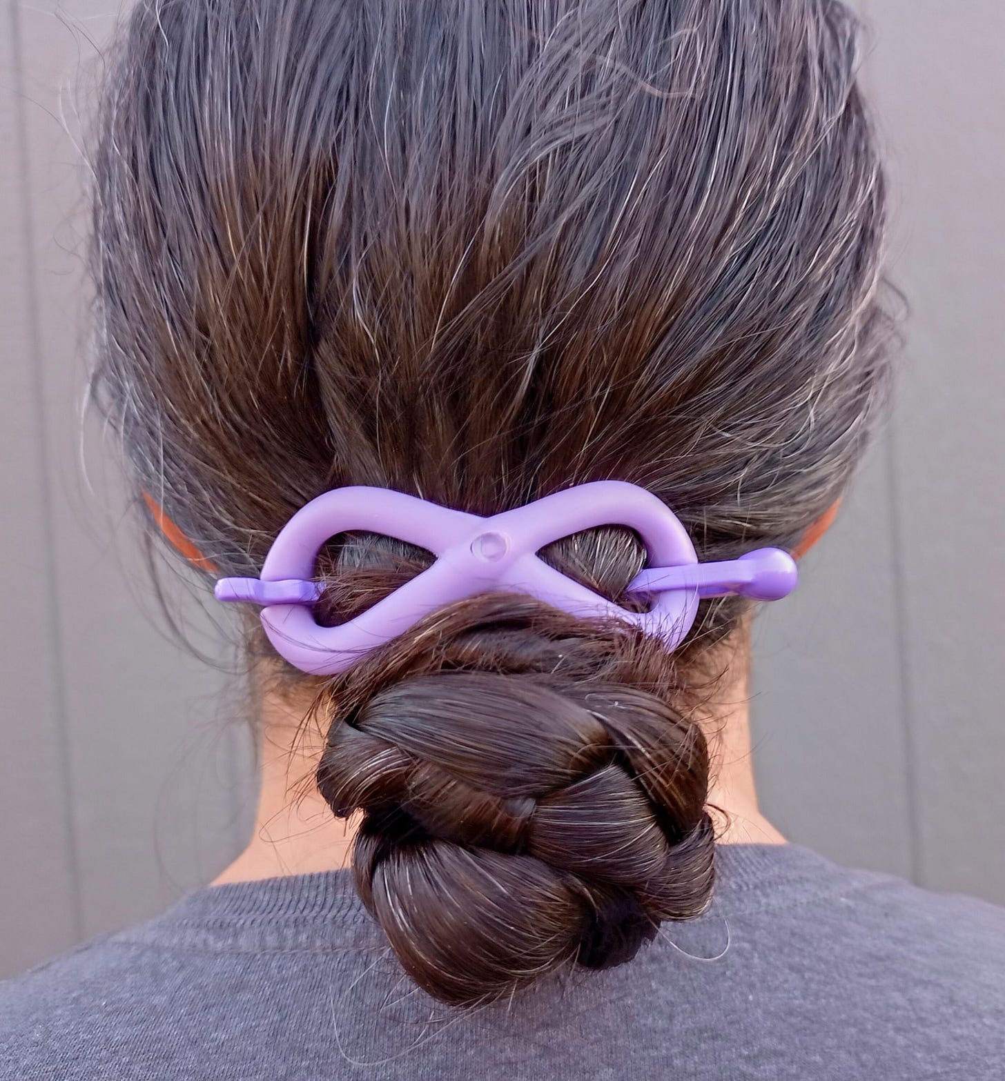 Woman with brown hair in a braided bun with purple Flexi hair clip