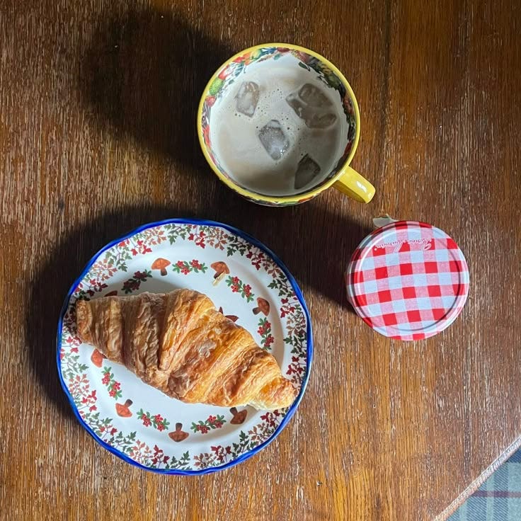 This may contain: two plates with croissants on them next to a cup of ice cream