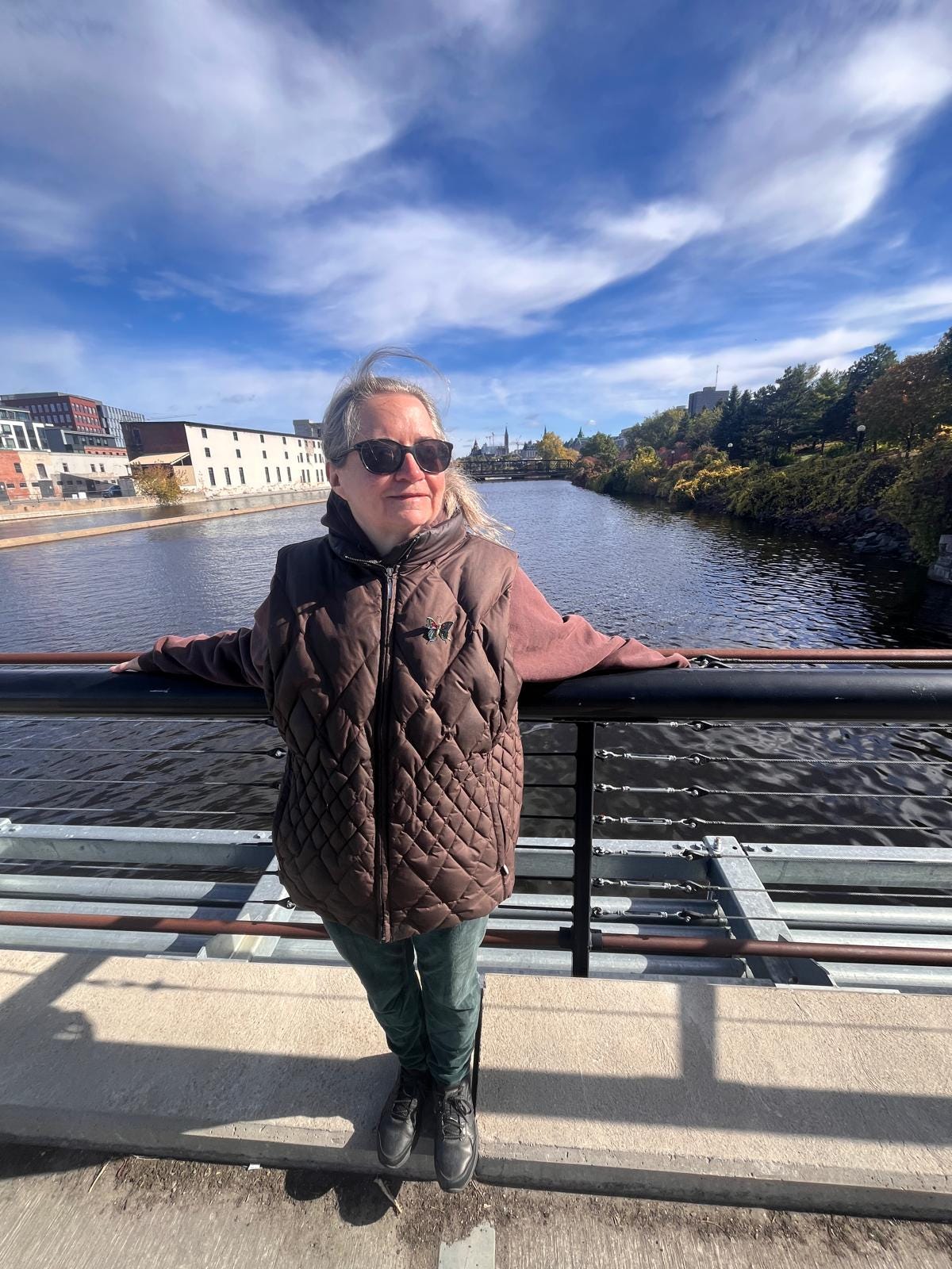 Amanda Earl standing on a bridge with a blue sky above.