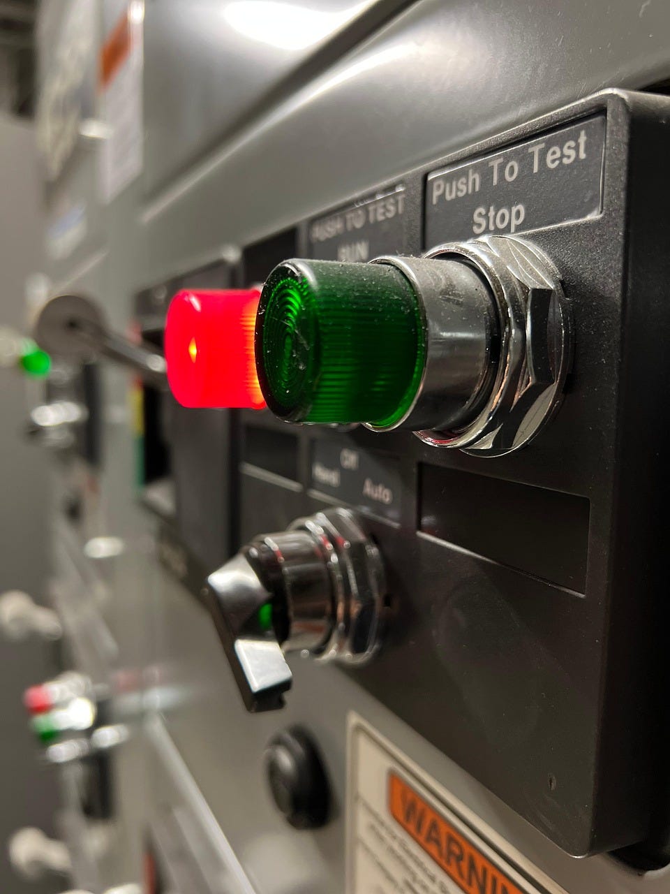 Two buttons, one red and one green. The green button is labeled "Push to test stop." The red button is labeled "Push to test run," and is glowing.