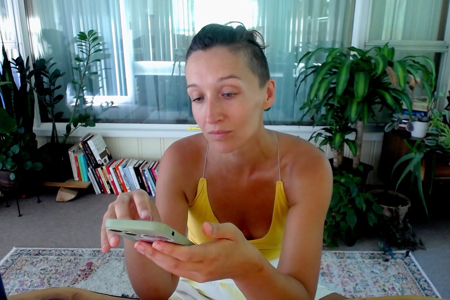 Tarzan looking at her phone and tapping on it with a face that says, “I am not impressed”