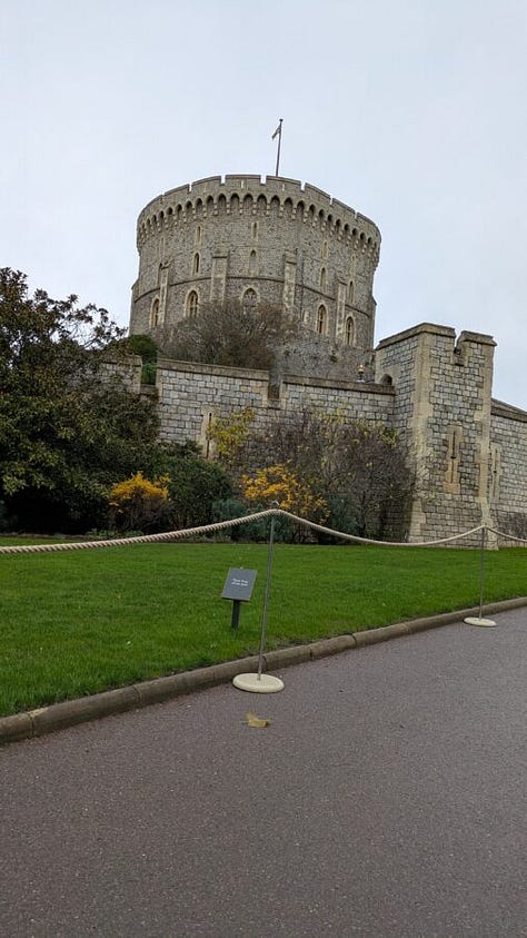 The first image shows a traditional British afternoon tea setup with tiered trays of scones, sandwiches, pastries, and desserts, along with a teapot and teacup on a floral-patterned table setting in a cozy café. The second image depicts a stone pathway leading toward the entrance of a grand historic castle tower surrounded by greenery. The third image shows another view of the same castle, focusing on a large round tower with a flag on top, stone walls, and manicured lawns bordered by a rope barrier.