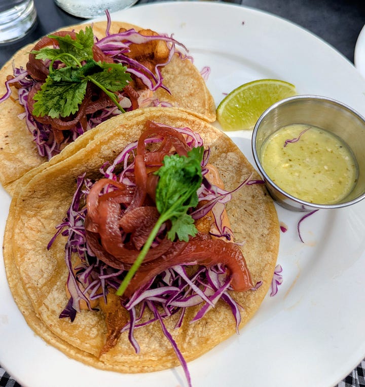 Left to right: Crispy fish tacos covered with purple cabbage slaw, red onions, and cilantro with a salsa verde on the side; Eggs Benedict with ham covered in hollandaise served with a side of fries.