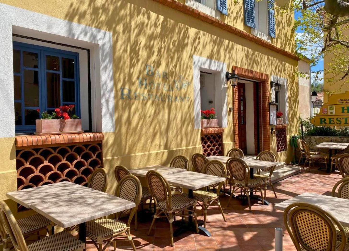 Empty terrace at Grand Hôtel Bain, Comps-sur-Artuby. Dappled light through plane trees, bistro chairs and marble tables. Empty terrace at Grand Hôtel Bain, Comps-sur-Artuby. Dappled light through plane trees, bistro chairs and marble tables.