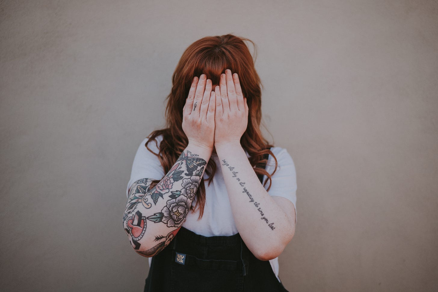 woman covering her face in front of wall photo