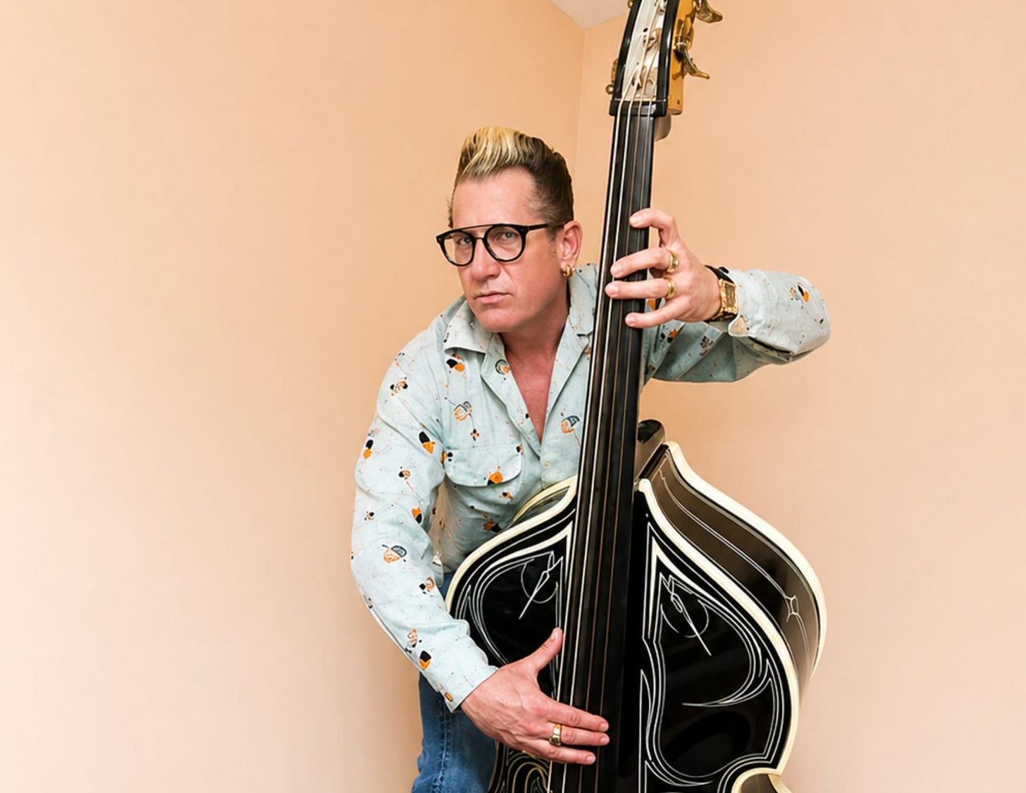 Lee Rocker of the Stray Cats sits on a stool holding his bass Lee Rocker of the Stray Cats sits on a stool holding his bass