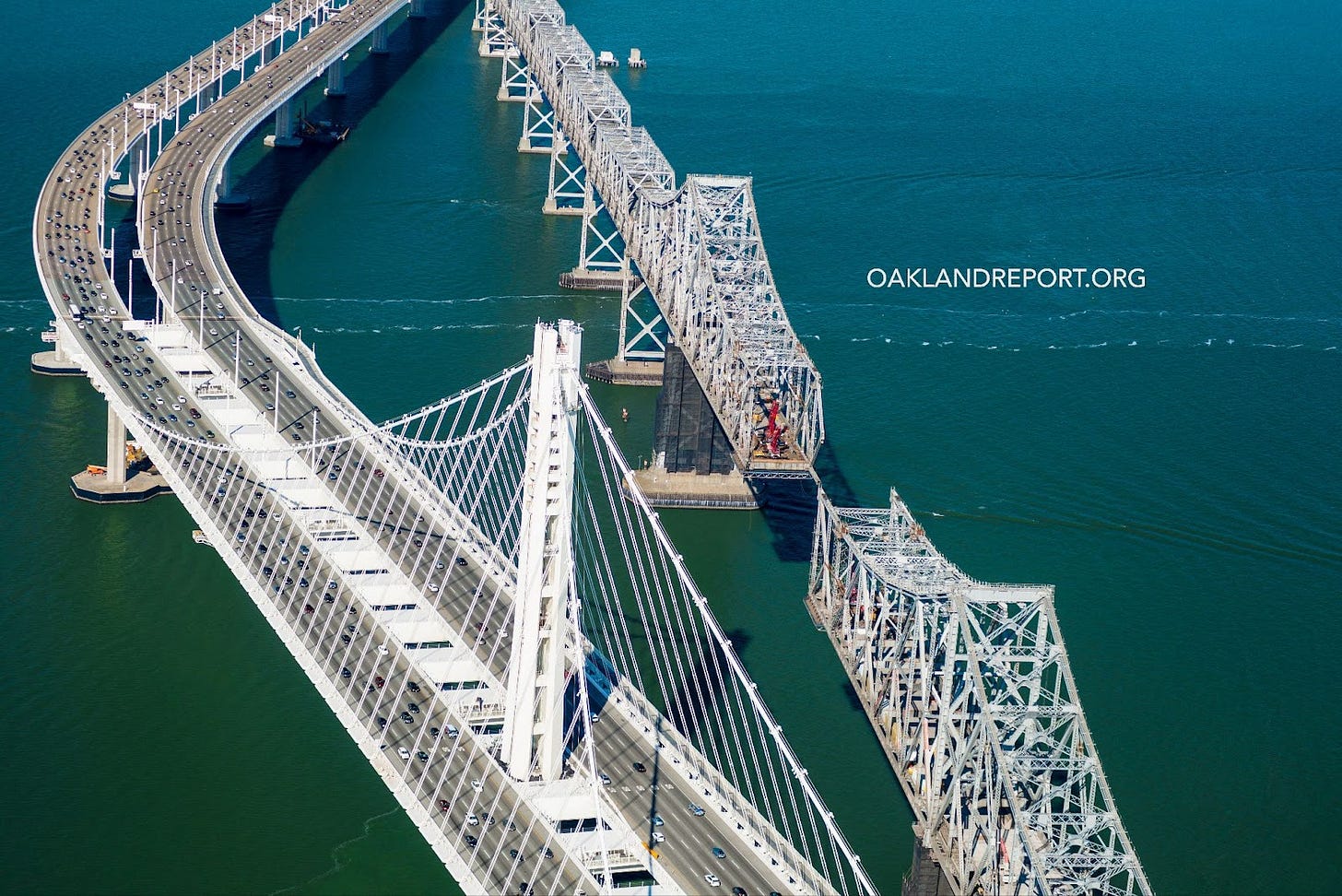 The new Bay Bridge single-tower, self-anchored eastern span side-by-side with the old, seismically unsafe cantilever span, during the latter’s deconstruction. Oakland, California, 2014. (Image source: Oakland Report / Adobe Stock)