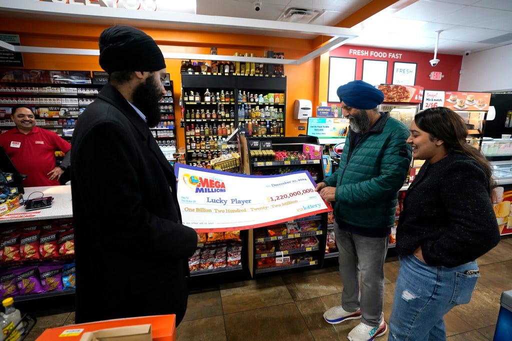 Ishar Gill, his father and sister Jaspal Singh and sister Jaspeet Gill look at an enlarged check giving to the family's store for selling the winning Mega Millions ticket. Ishar Gill, his father and sister Jaspal Singh and sister Jaspeet Gill look at an enlarged check giving to the family's store for selling the winning Mega Millions ticket.