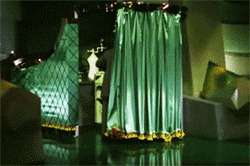 Toto pulls back green curtain to reveal the Wizard of Oz