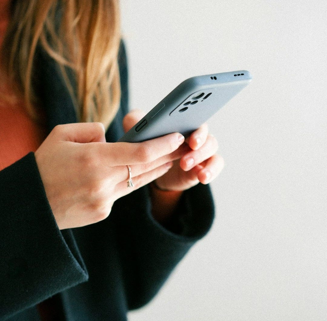 a woman holding a cell phone in her hands a woman holding a cell phone in her hands