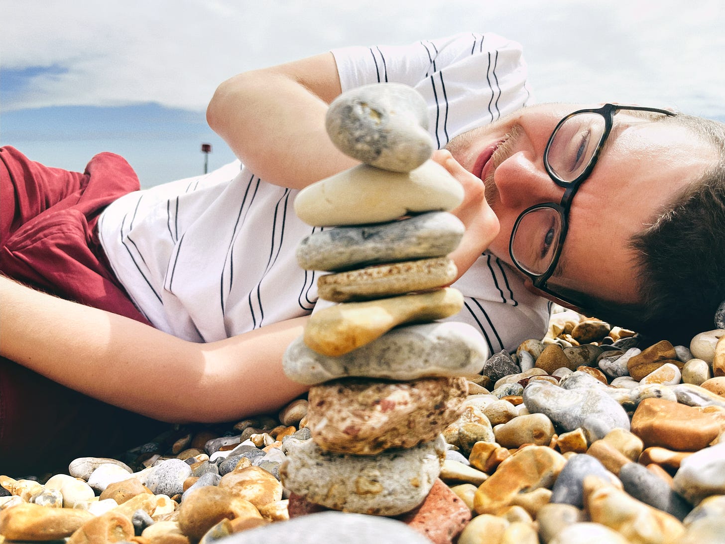 Person stacking and balancing pebbles on the seashore
