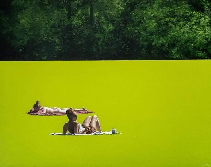 This may contain: two people are laying on the grass in front of some trees and green water,