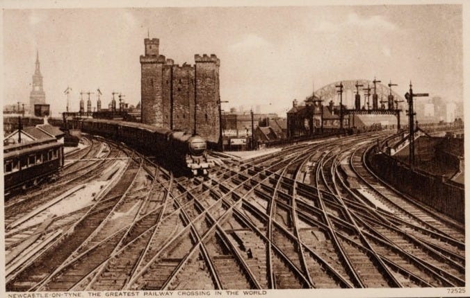 Historic black and white postcard of Newcastle railway crossing, showcasing multiple railway tracks and towers in the background.