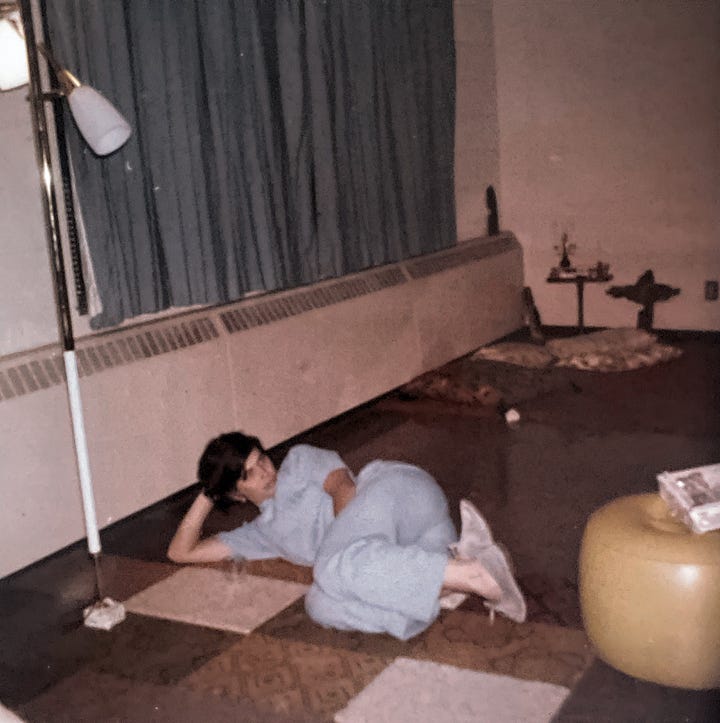 A woman in flowered pants and yellow shit sitting on an orange bedspread and the same woman lying on the floor on her side in blue pajamas