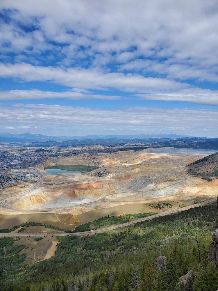 View of Butte, MT from above, featuring prominent open mining pit filled with blue water.