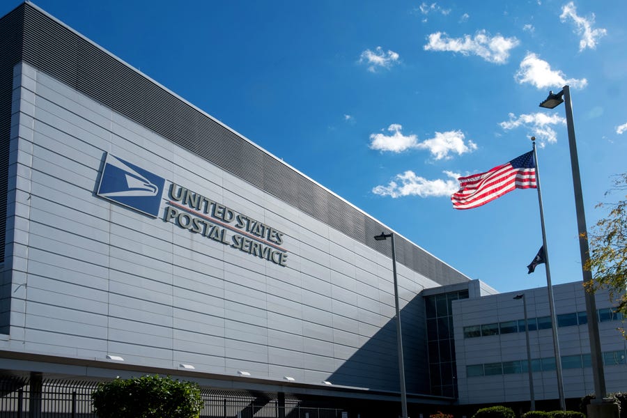 Exterior of a United States Postal Service building with an American flag flying Exterior of a United States Postal Service building with an American flag flying