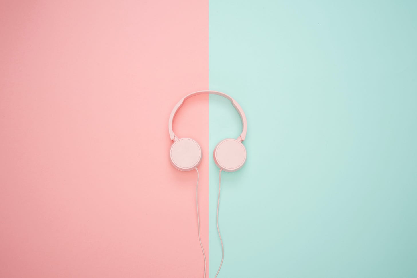 A stock image of pink headphones on a pink and mint green background