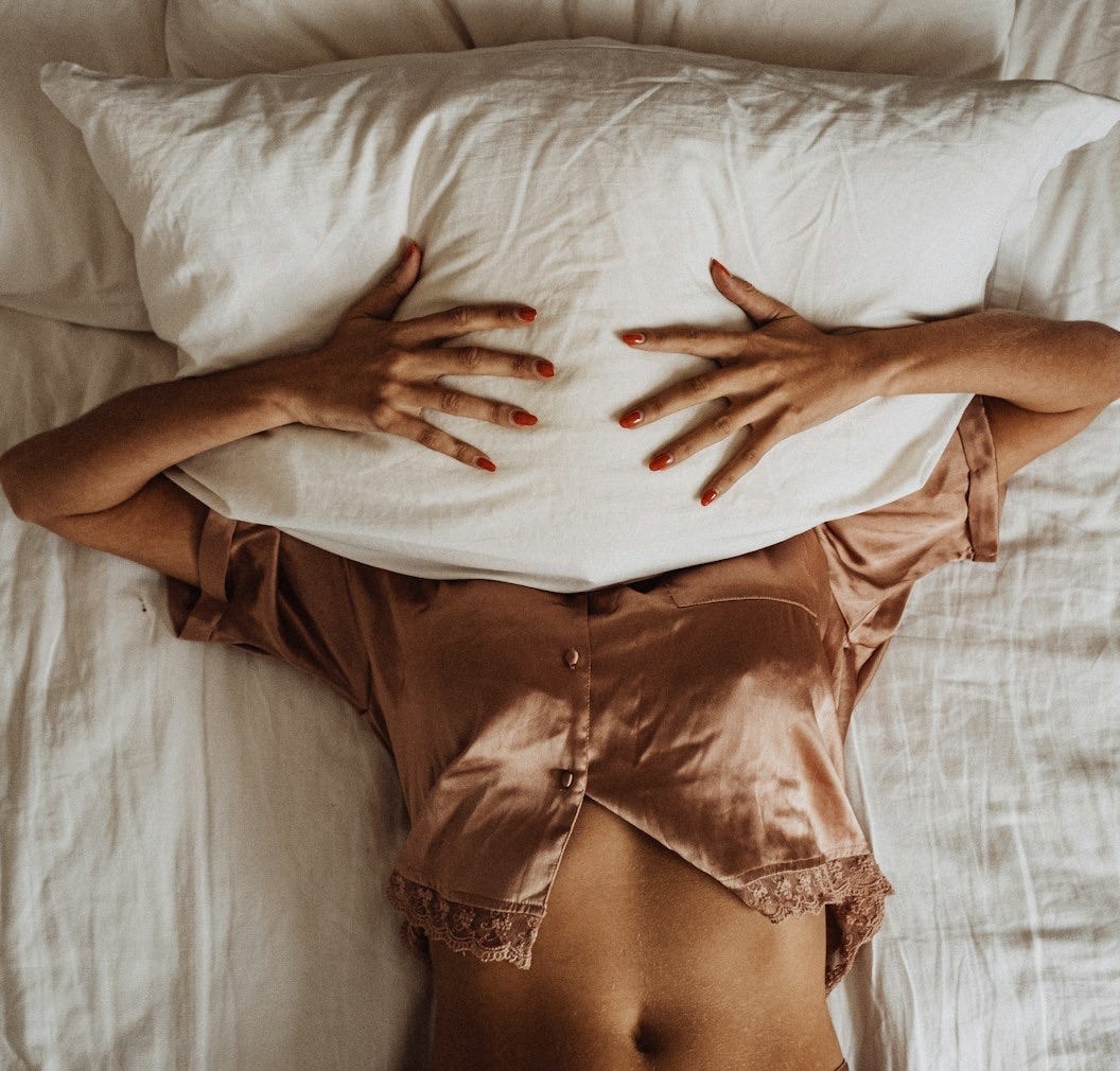 a woman laying in bed with her hands on a pillow a woman laying in bed with her hands on a pillow