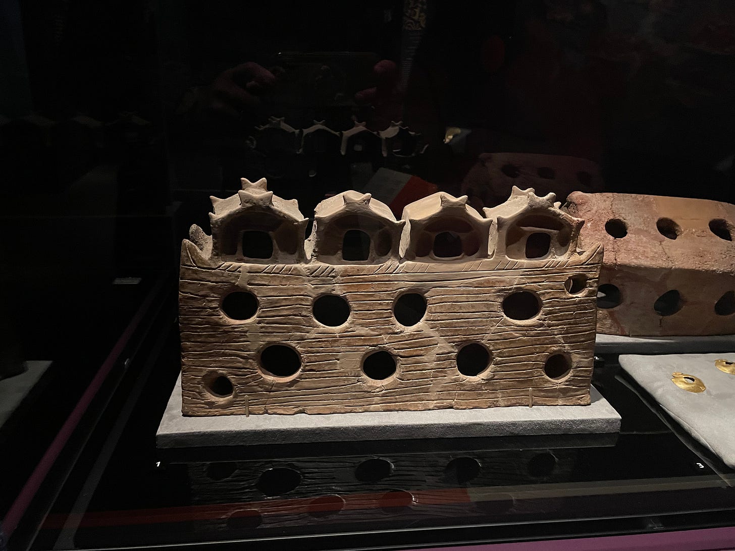 carving of what looks like four rowhouses on top of a hill with holes dug out of the center