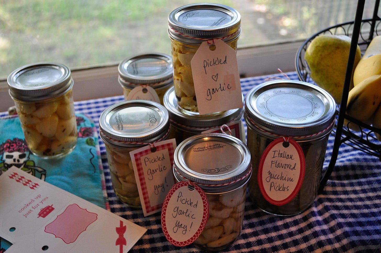 a group of canning jars on a table featuring zucchini pickles and pickled garlic