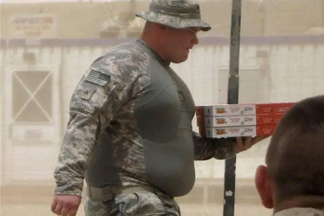 A person in military uniform carrying pizza boxes. The uniform includes camouflage clothing and a hat. The individual has a visible physique. A person in military uniform carrying pizza boxes. The uniform includes camouflage clothing and a hat. The individual has a visible physique.