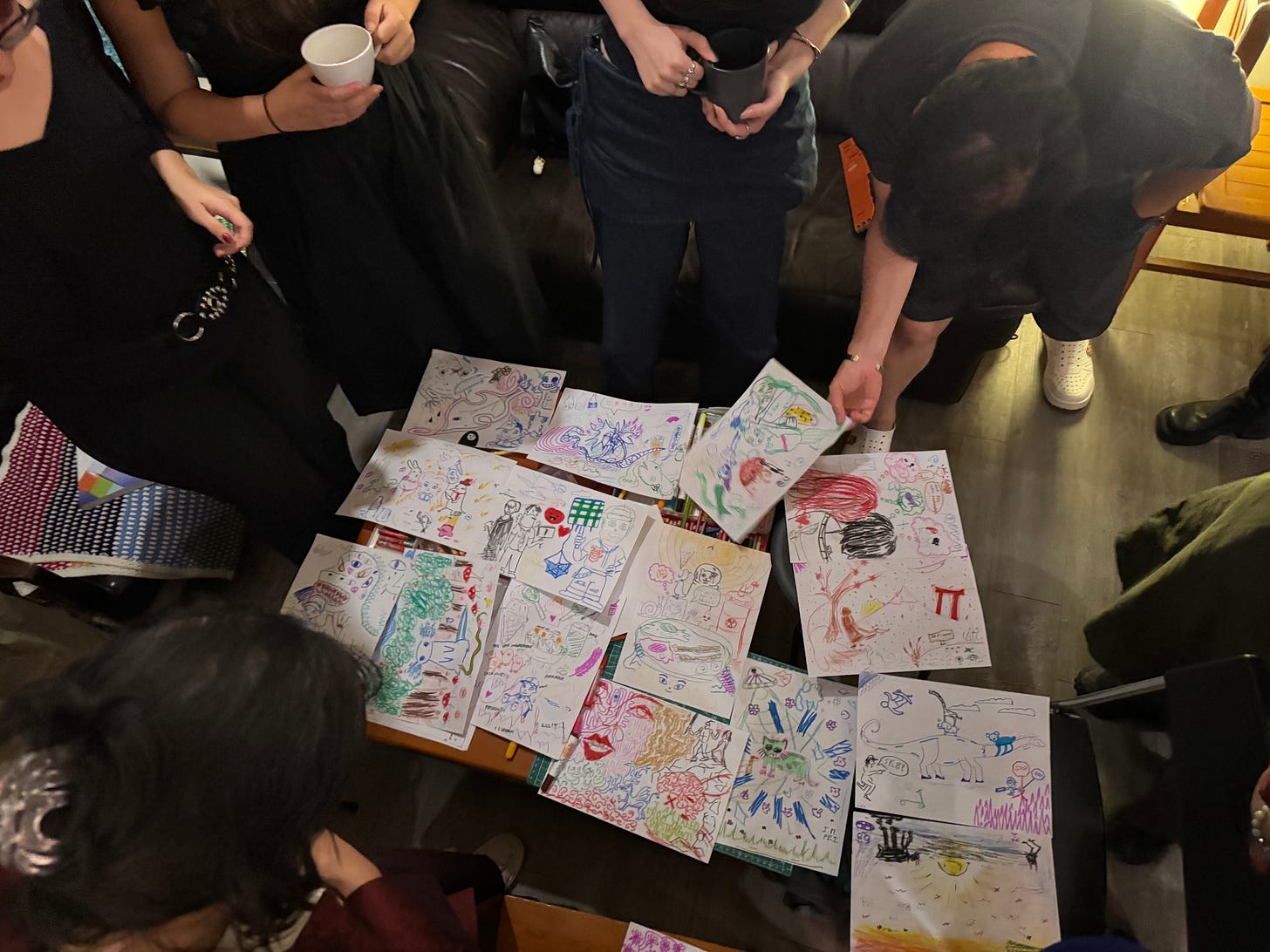 Horizontal photo of many attendees in a circle admiring creative drawings from Pen Club