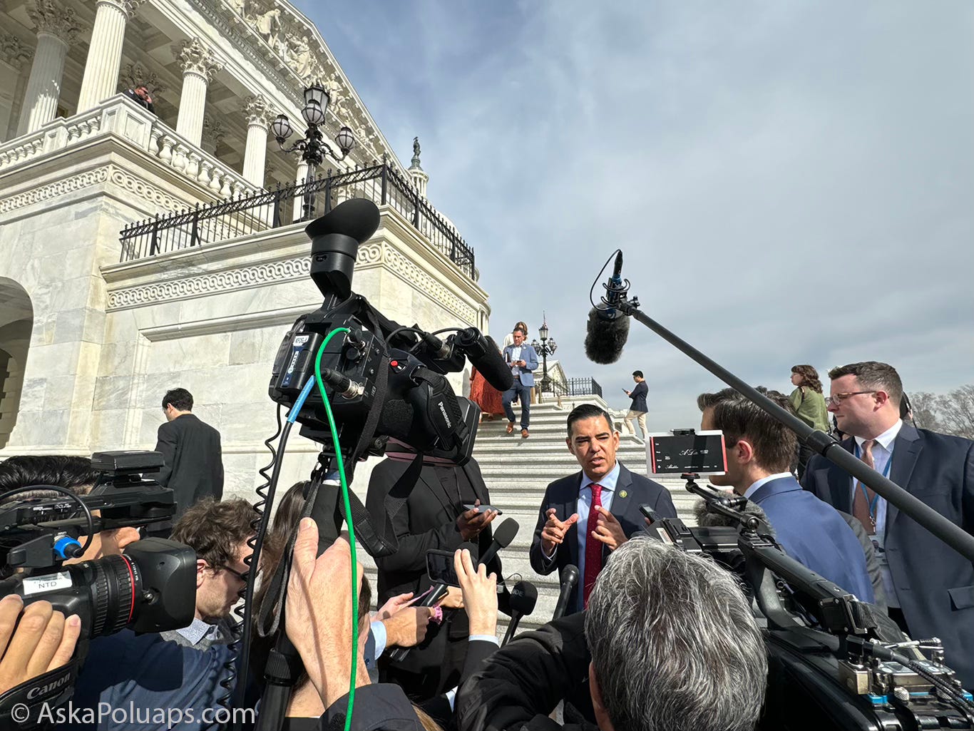 TV cameras and journalists ask a politician questions on US Capitol steps © AskaPolUAPs.com 
