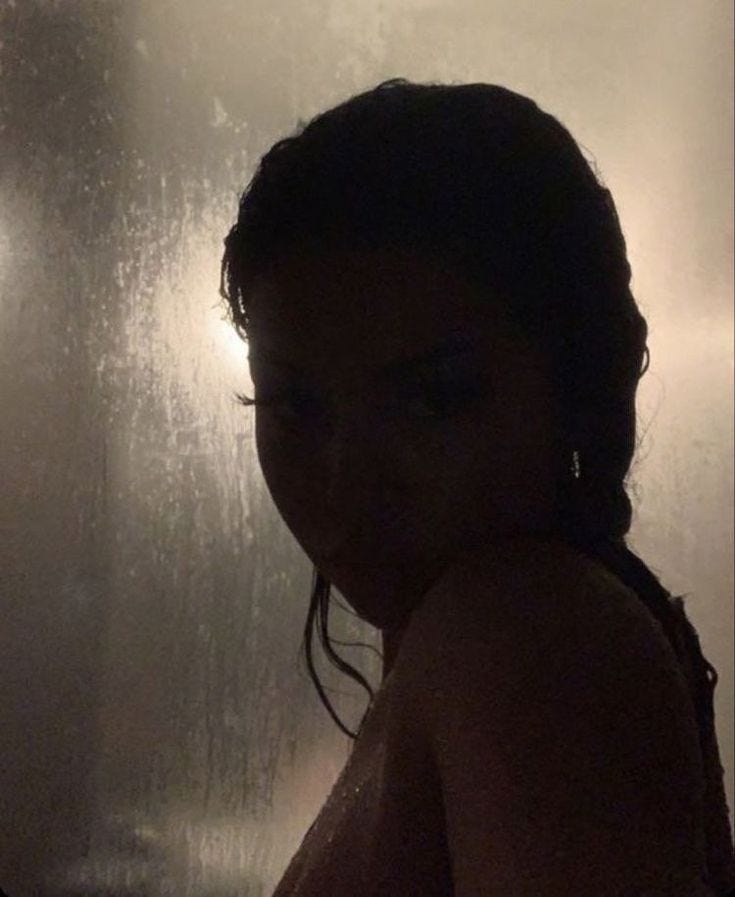 This may contain: a woman standing in front of a shower head
