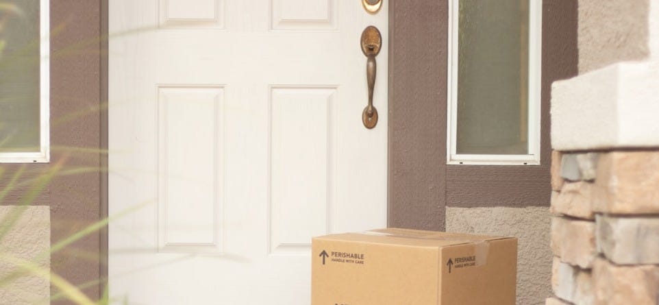 brown cardboard box beside white wooden door